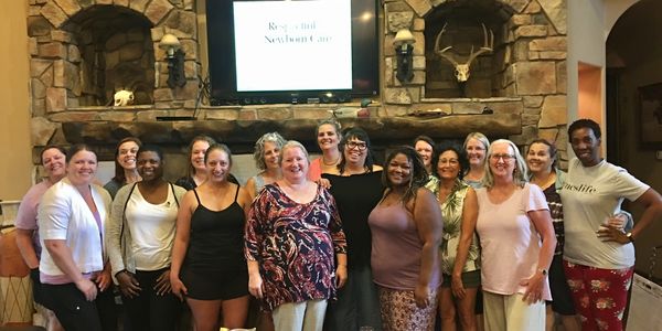 Danielle McLellan-Bujnak standing with Respectful Care® students in front of a large stone fireplace