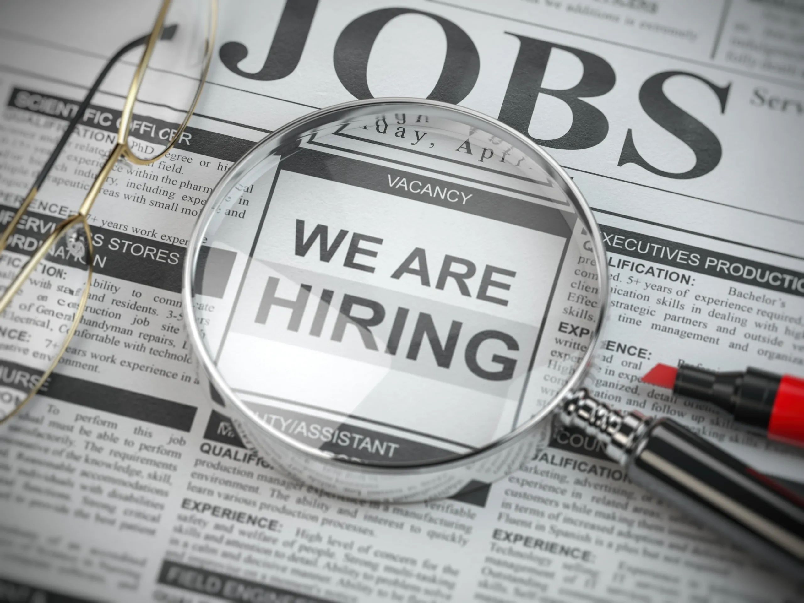 Magnifying glass on job vacancy ad in newspaper.