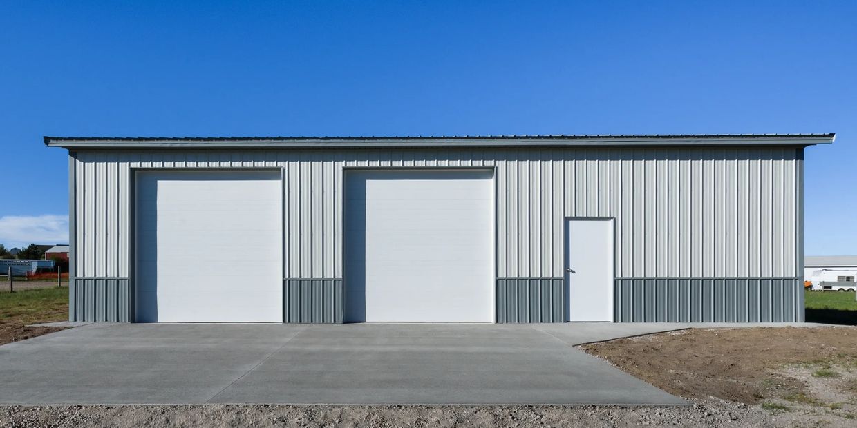 A metal building with two large garage doors and one pedestrian door.