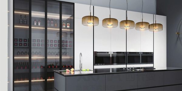 Modern kitchen with glass cabinets and hanging lights.
