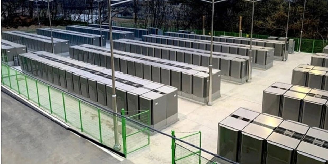 Rows of large industrial battery units outdoors under a canopy.