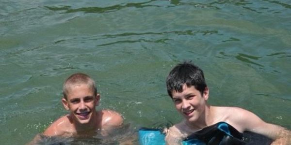 Two boys swimming and smiling in water.