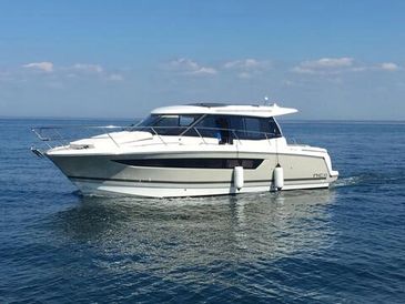 A sleek white motor yacht cruising on calm blue waters under a clear sky.