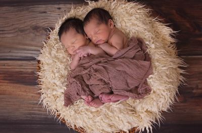 Two newborn babies sleeping peacefully in a cozy basket.