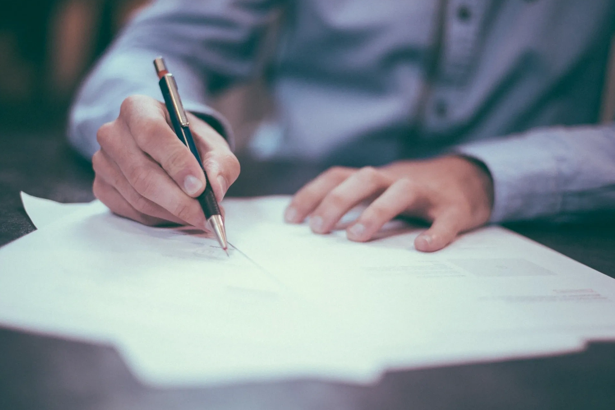 Man signing documents with a pen.