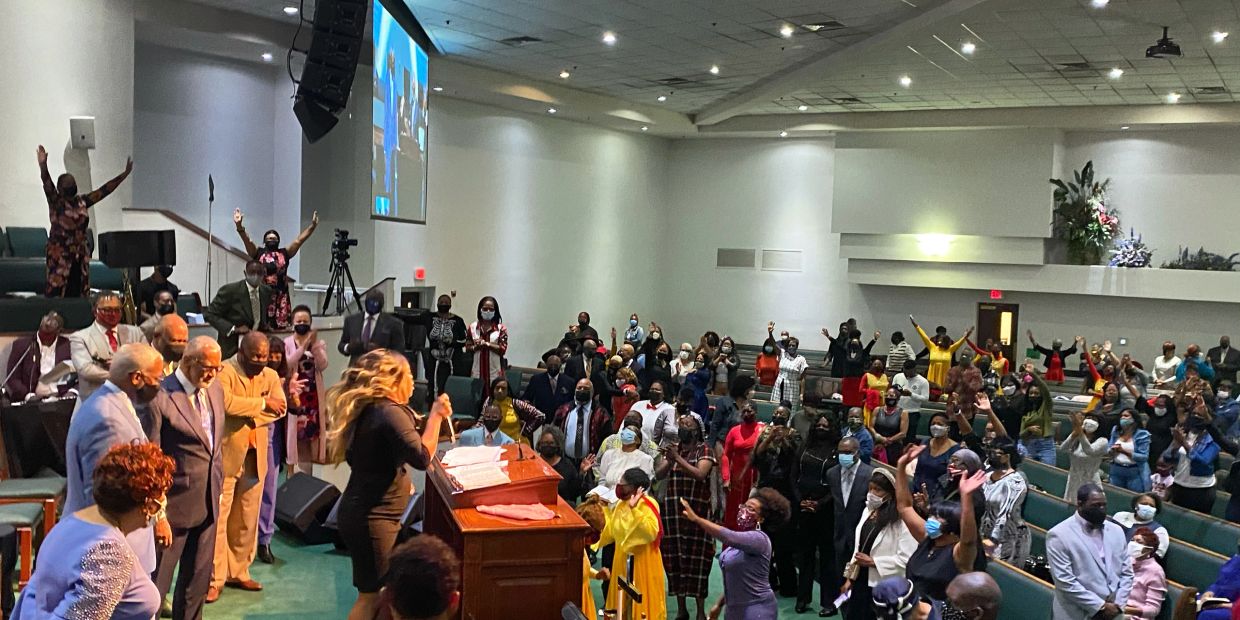 Congregation worshiping in a church service with raised hands.