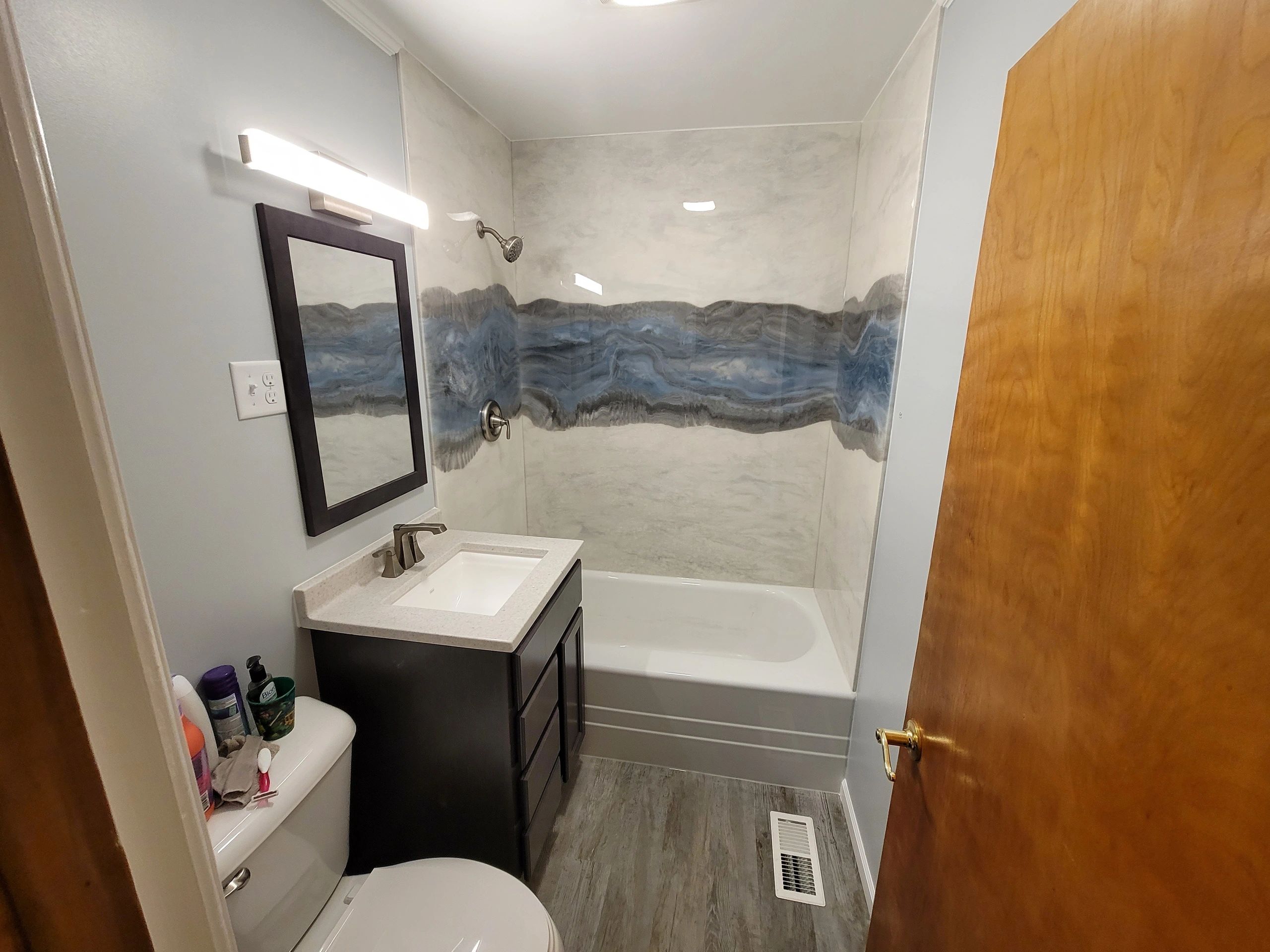 Compact bathroom with modern fixtures and blue-gray shower tiles.