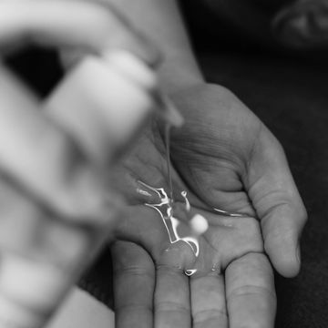 Close-up of a hand with clear liquid being dispensed.