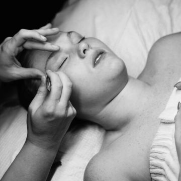 Person receiving eyebrow grooming in a calming setting.