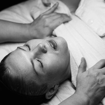 Black and white portrait of a woman lying down with eyes closed, appearing relaxed.