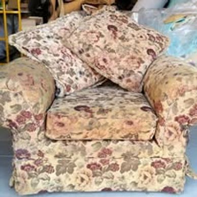 Floral-patterned armchair with cushions in a storage setting.