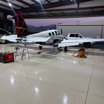Small airplane inside a well-lit hangar with tools and a white truck nearby.