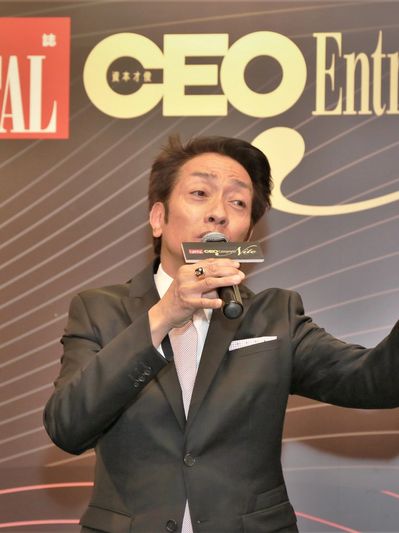 Man in black suit speaking at an event.
