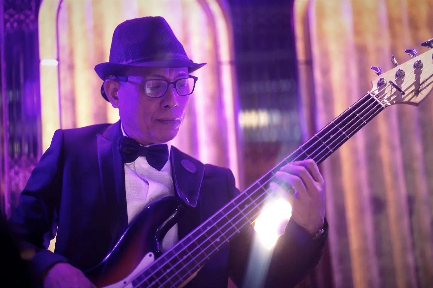 Man in a hat playing bass guitar.