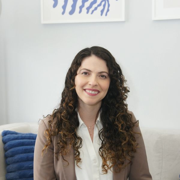 Smiling woman with curly hair sitting indoors.