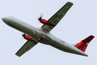 A turboprop airplane flying with red and white colors.