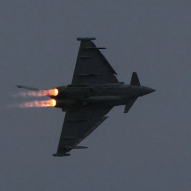 Military jet flying with afterburners on.
