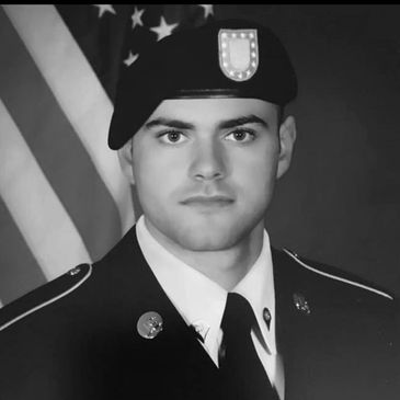 Portrait of a young soldier in uniform with American flag background.