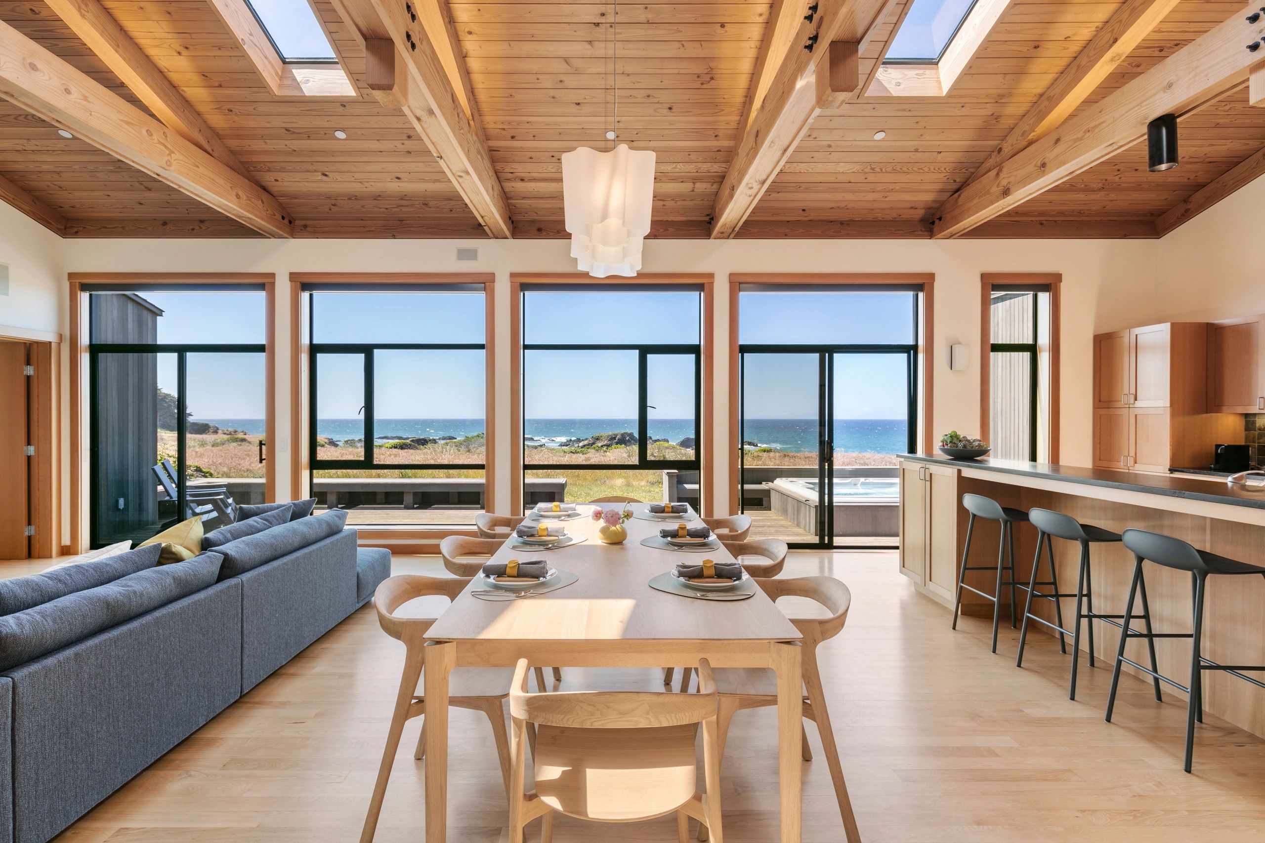 Modern dining area with ocean view and wooden ceiling.