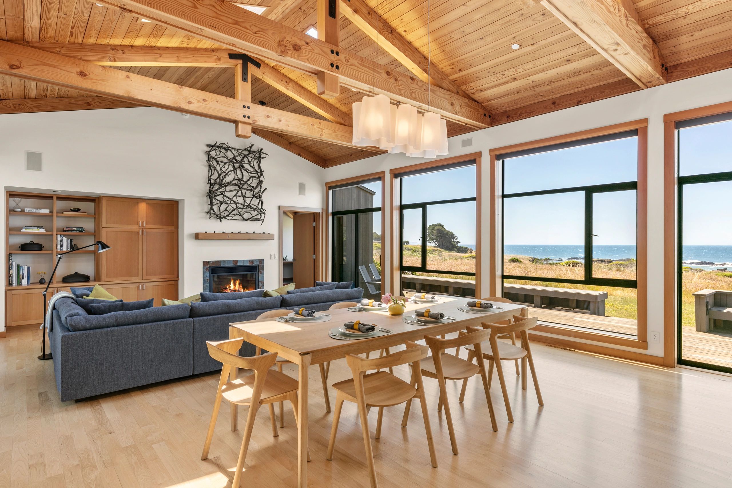 Bright coastal living and dining area with wooden ceiling beams.
