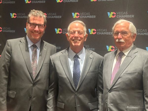 Three men in suits posing at a Vegas Chamber event.