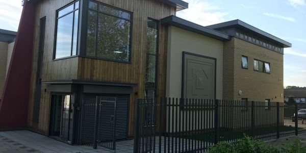 Modern building with wood and brick exterior behind a black metal fence.