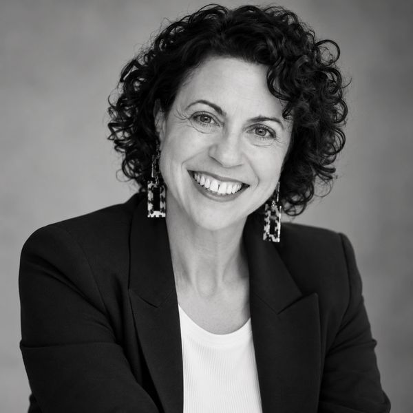 Smiling woman with curly hair in a blazer.