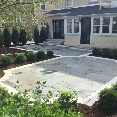 Stone patio with white border and landscaping.