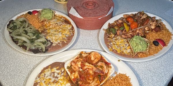Three plates of Mexican food with rice, beans, and tacos.