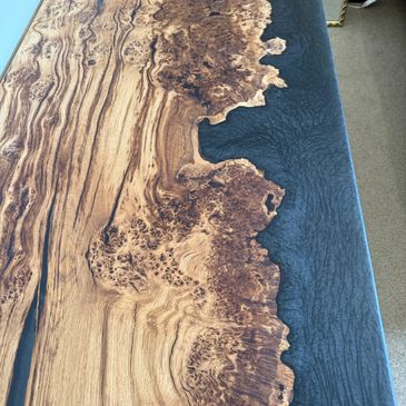Wooden table with natural edge and dark epoxy resin.