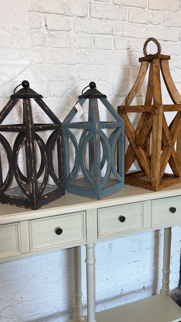 Three decorative lanterns on a white console table.