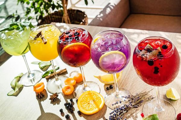 Colorful cocktails with fruit garnishes on a sunny table.