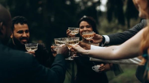Group of friends toasting with champagne glasses outdoors.
