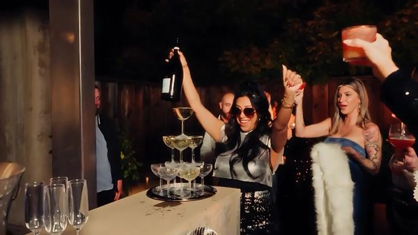 Woman holding a champagne bottle celebrating with friends at a party.