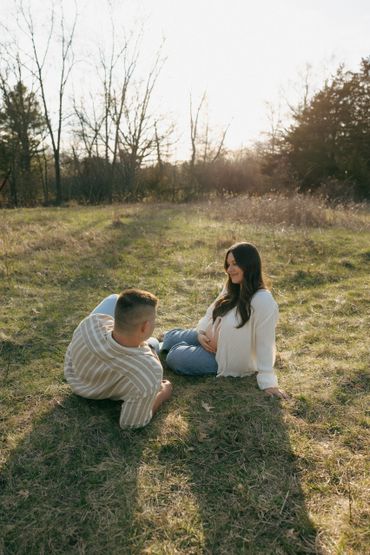 Couple enjoying a sunny afternoon outdoors, woman sitting and man lying on grass.