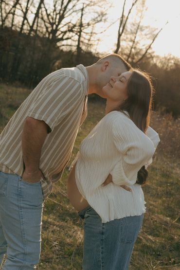 Couple sharing a tender moment outdoors, celebrating pregnancy.