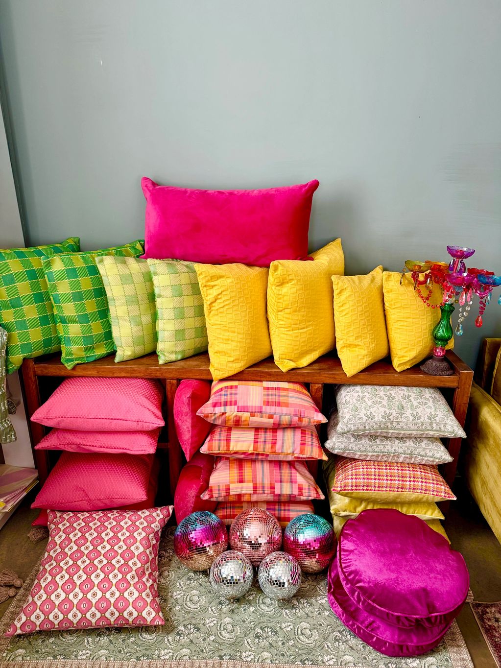 Vibrant cushions and disco balls arranged on a wooden shelf.