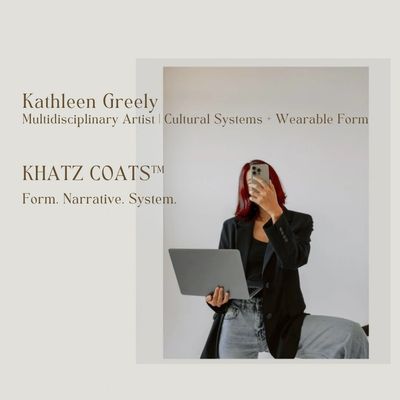 Artist Kathleen Greely holding laptop, capturing a mirror selfie in casual chic attire.