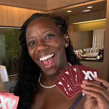 Smiling woman holding several red cards, enjoying a fun moment.