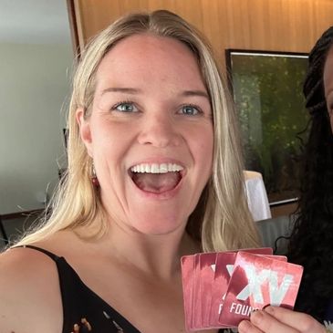 Smiling woman holding several red cards, enjoying a fun moment.