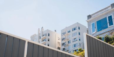 View of white apartment buildings behind a fence.