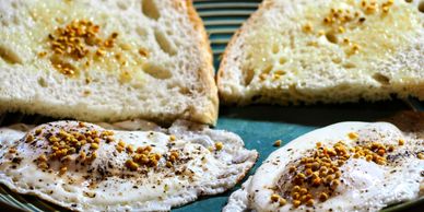 Two farm fresh eggs and sourdough toast garnished with pepper and bee pollen. 