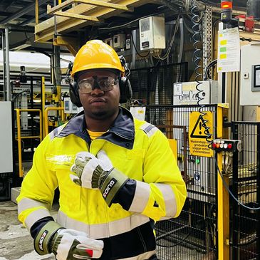 Worker in safety gear standing in an industrial setting.