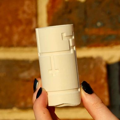 Hand holding a white cylindrical object with puzzle-like grooves.