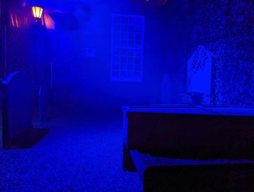 A dimly lit room with blue lighting and furniture silhouettes.