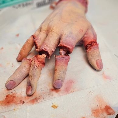 Realistic severed fingers with blood on a white surface.