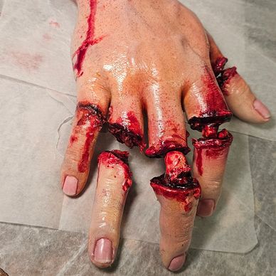 A realistic special effects hand with severed and bloody fingers.