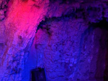 A cave-like interior illuminated with vibrant purple and pink lighting.