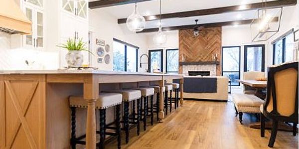 Spacious modern kitchen with wooden floors and bar stools.