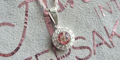 Silver pendant with clear stones on a chain.